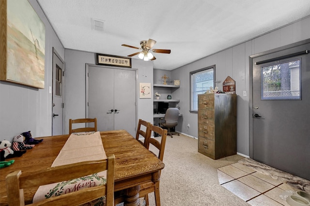 dining area featuring light carpet, a textured ceiling, and ceiling fan