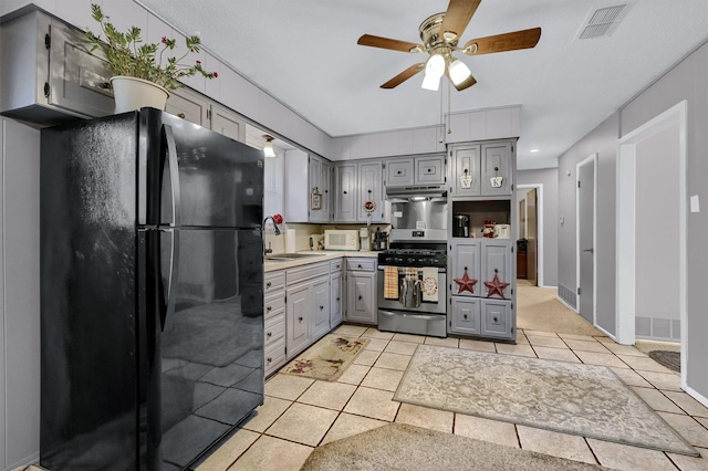 kitchen with sink, light tile patterned floors, black refrigerator, gray cabinetry, and gas range