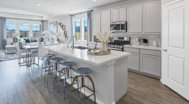 kitchen featuring a kitchen bar, appliances with stainless steel finishes, sink, a center island with sink, and dark hardwood / wood-style floors