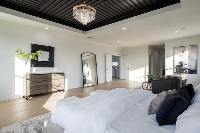 bedroom featuring a raised ceiling, crown molding, a notable chandelier, and light hardwood / wood-style floors