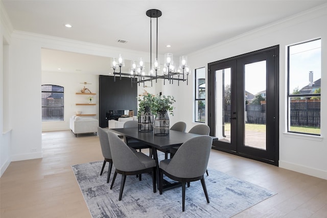 dining space with ornamental molding, light hardwood / wood-style floors, and french doors