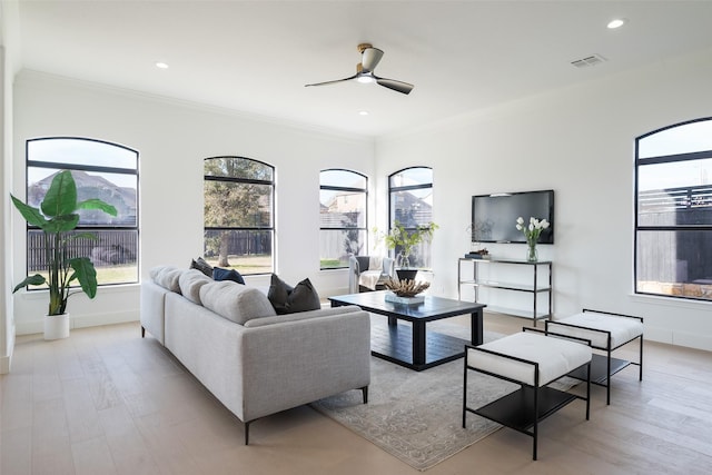 living room with light hardwood / wood-style flooring, ornamental molding, and ceiling fan