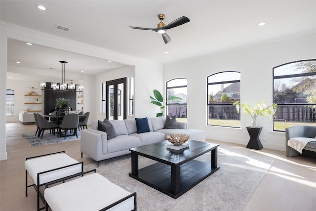 living room featuring crown molding, ceiling fan with notable chandelier, and light wood-type flooring