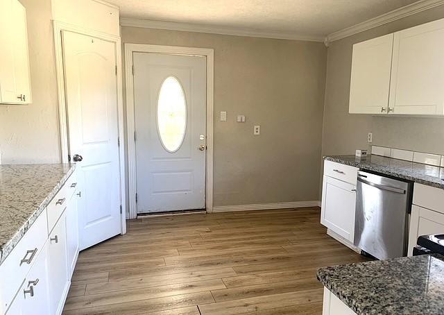 kitchen featuring dishwasher, light wood-type flooring, white cabinetry, and dark stone counters