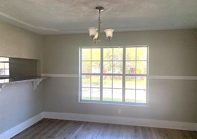 unfurnished dining area featuring a wealth of natural light, hardwood / wood-style floors, and a chandelier