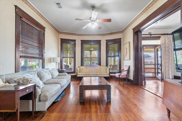 living room featuring dark hardwood / wood-style flooring, ceiling fan, and ornamental molding