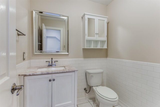 bathroom with tile patterned floors, vanity, tile walls, and toilet