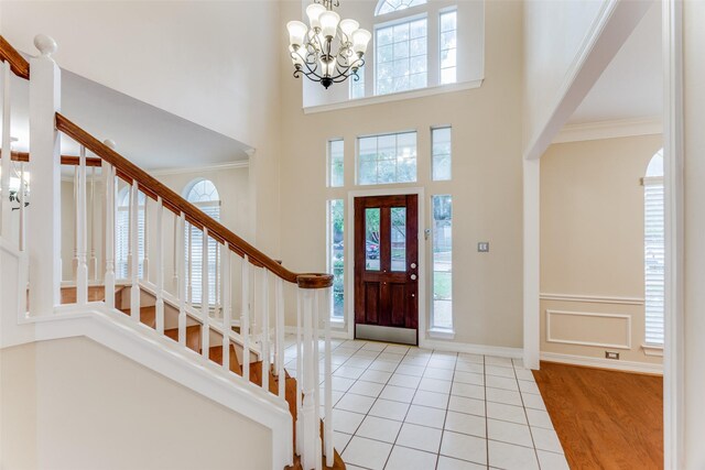 entrance foyer featuring crown molding, a chandelier, a high ceiling, and light wood-type flooring