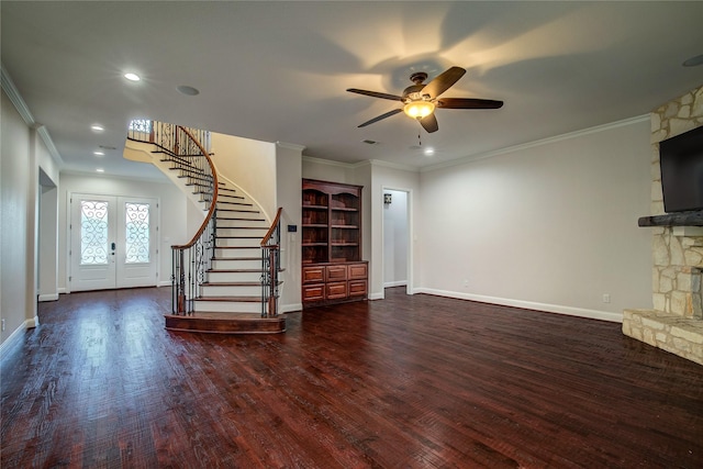 unfurnished living room with french doors, dark hardwood / wood-style floors, ornamental molding, and a stone fireplace