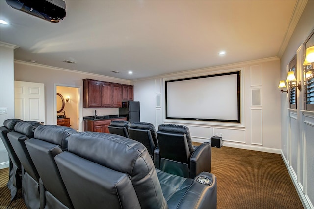 carpeted cinema room featuring crown molding and wet bar