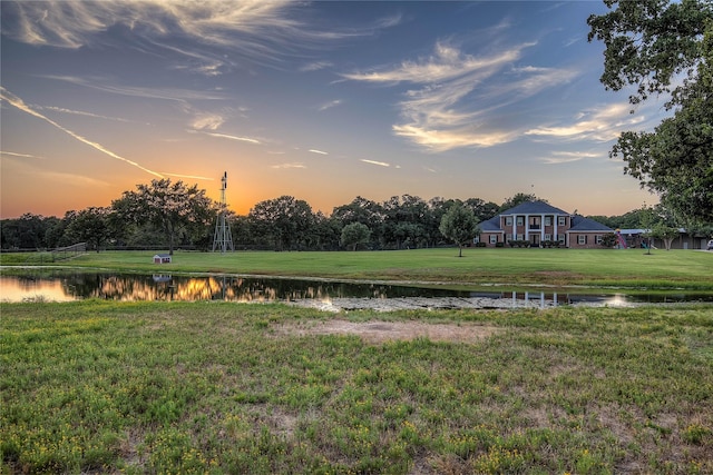 yard at dusk featuring a water view