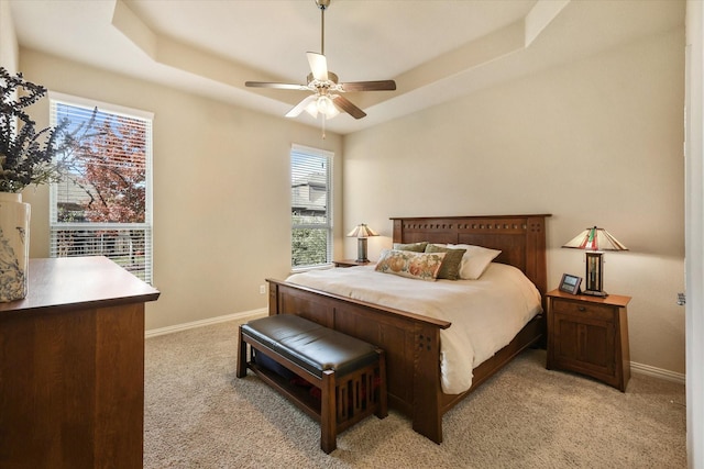 bedroom with a tray ceiling, ceiling fan, and light carpet