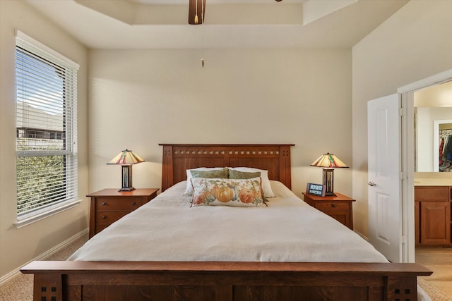 bedroom featuring light carpet, ensuite bathroom, and multiple windows