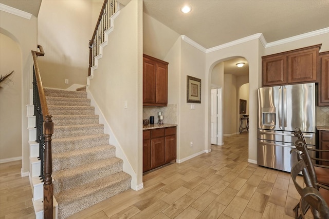 kitchen featuring stainless steel fridge, ornamental molding, backsplash, and light hardwood / wood-style flooring