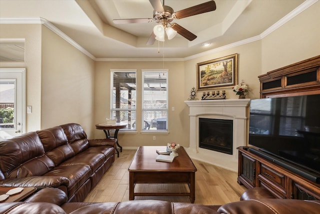 living room featuring light wood-type flooring, a tray ceiling, and ornamental molding