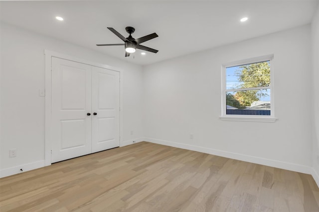 unfurnished bedroom featuring ceiling fan, light hardwood / wood-style floors, and a closet