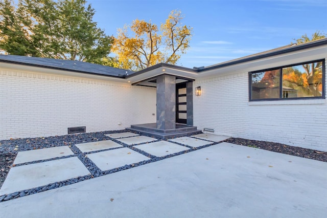 view of exterior entry with a patio