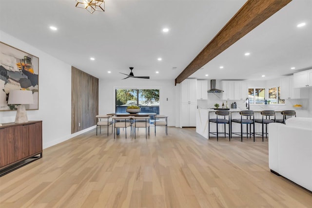 dining space featuring beam ceiling, light wood-type flooring, plenty of natural light, and ceiling fan