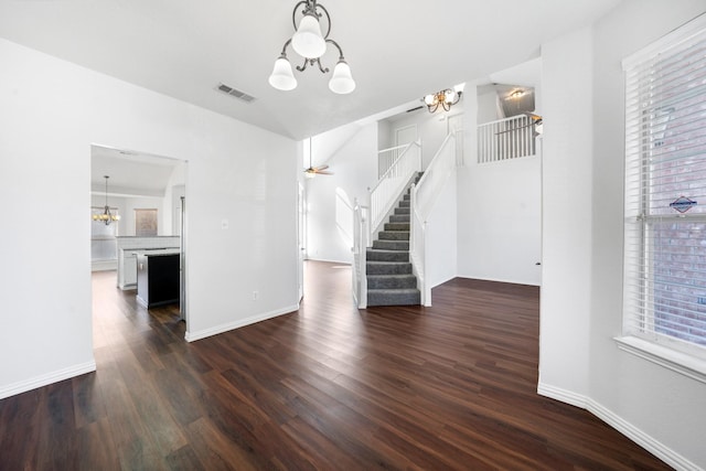 unfurnished living room featuring dark hardwood / wood-style floors and ceiling fan with notable chandelier