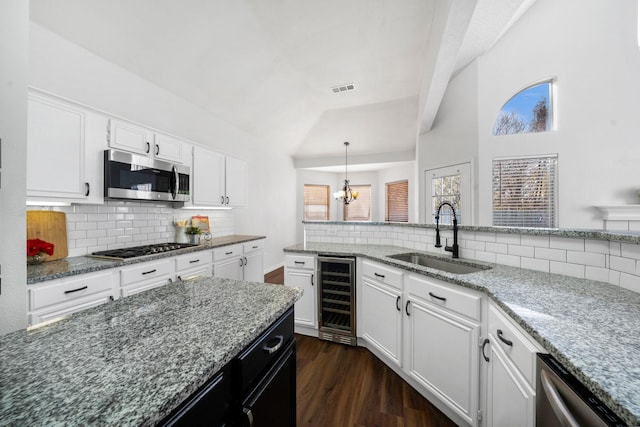 kitchen with white cabinets, stainless steel appliances, beverage cooler, and sink