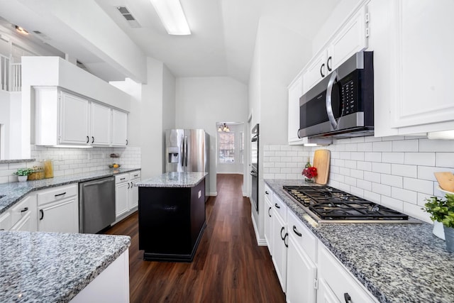 kitchen featuring a center island, light stone counters, white cabinetry, and stainless steel appliances