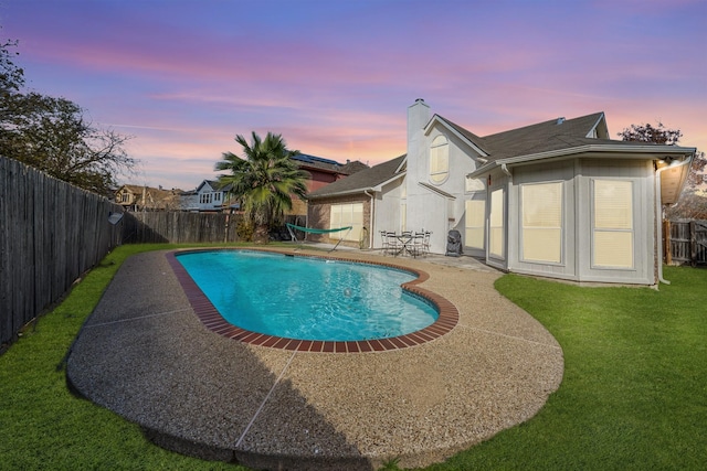 pool at dusk with a yard and a patio