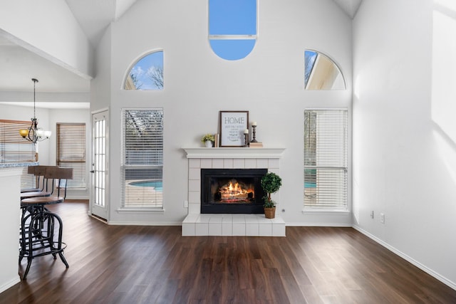 unfurnished living room featuring a tile fireplace, high vaulted ceiling, a wealth of natural light, and dark hardwood / wood-style flooring