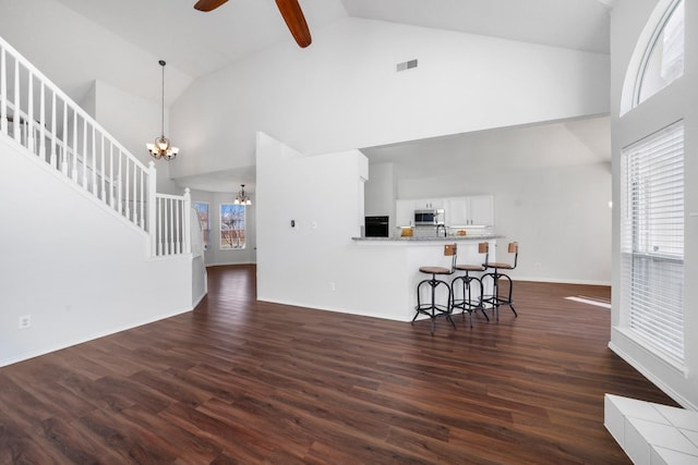 living room featuring plenty of natural light, dark wood-type flooring, and high vaulted ceiling