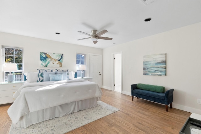 bedroom featuring light wood-type flooring, multiple windows, and ceiling fan