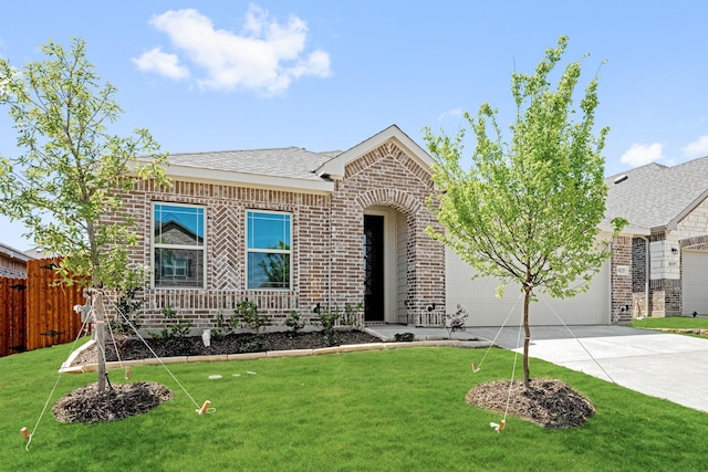 single story home featuring a front yard, fence, brick siding, an attached garage, and driveway