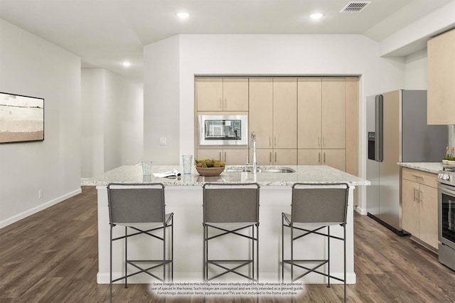 kitchen featuring visible vents, stainless steel appliances, light brown cabinetry, and light stone counters