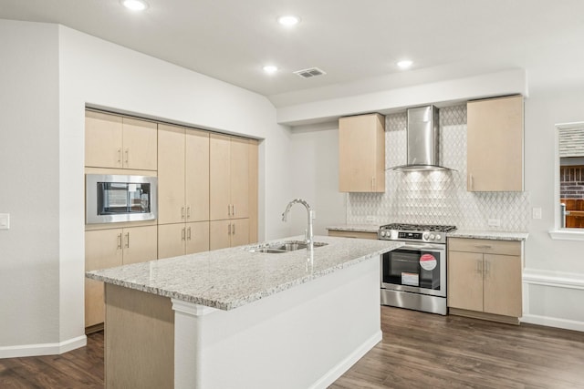 kitchen featuring wall chimney range hood, gas range, built in microwave, a sink, and light brown cabinetry