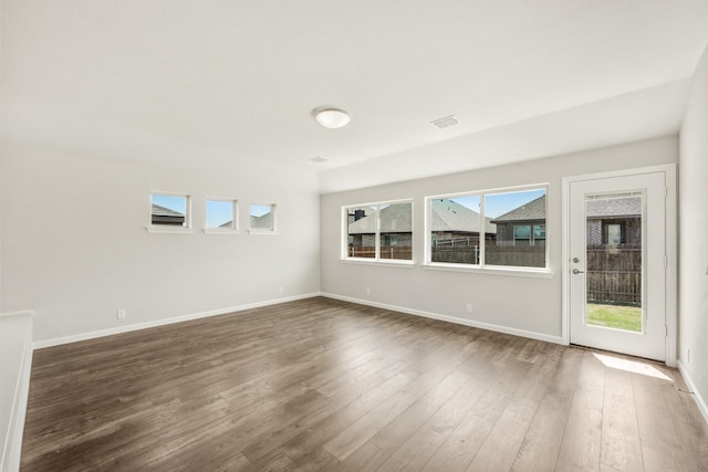 empty room with visible vents, baseboards, and dark wood finished floors
