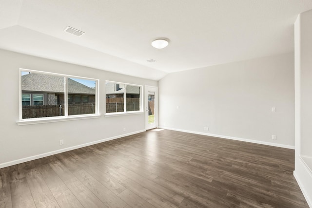 unfurnished room featuring dark wood-style flooring, visible vents, baseboards, and vaulted ceiling