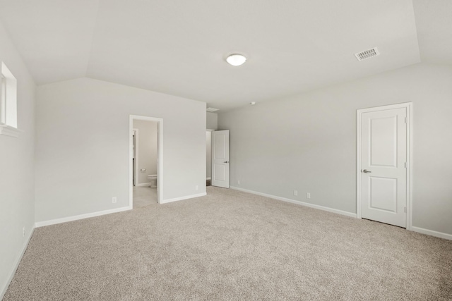 interior space with light carpet, visible vents, baseboards, and vaulted ceiling