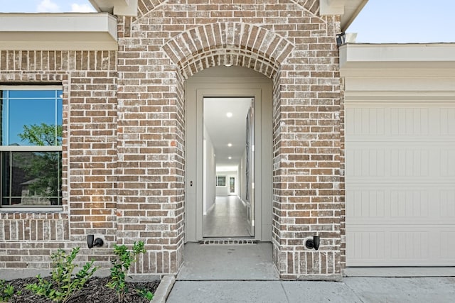 property entrance featuring an attached garage and brick siding