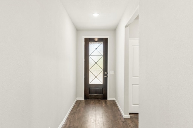 doorway with dark wood-type flooring and baseboards
