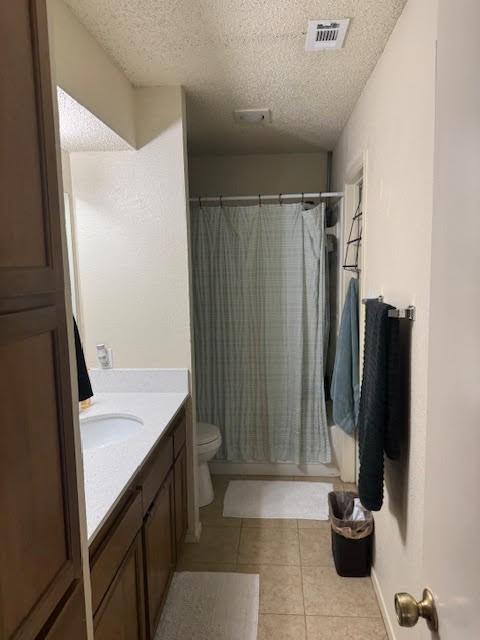 bathroom with tile patterned floors, vanity, a textured ceiling, and toilet