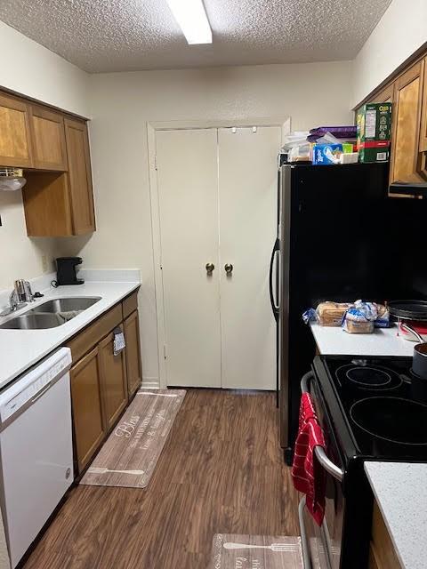 kitchen with a textured ceiling, dishwasher, dark hardwood / wood-style floors, and sink