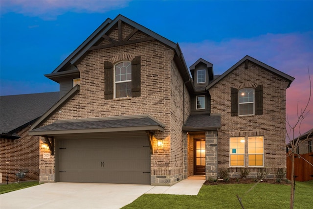 view of front of property with concrete driveway, a front lawn, a shingled roof, and brick siding