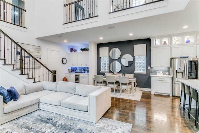 living room featuring a high ceiling, beverage cooler, and dark wood-type flooring