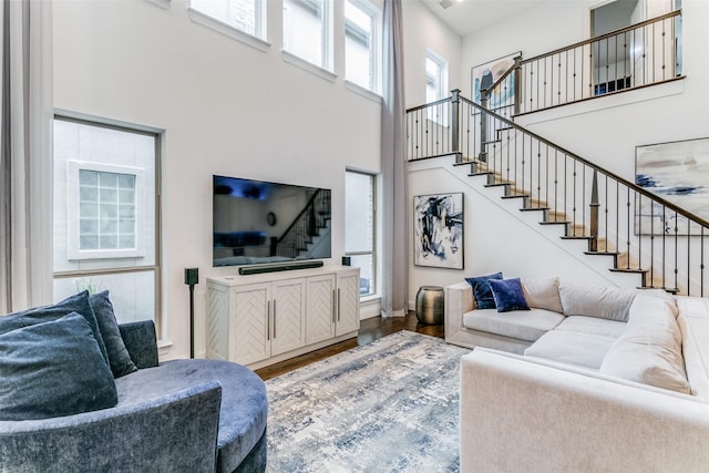 living room with hardwood / wood-style floors and a towering ceiling