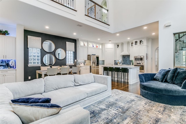 living room featuring dark hardwood / wood-style flooring, a healthy amount of sunlight, a high ceiling, and sink