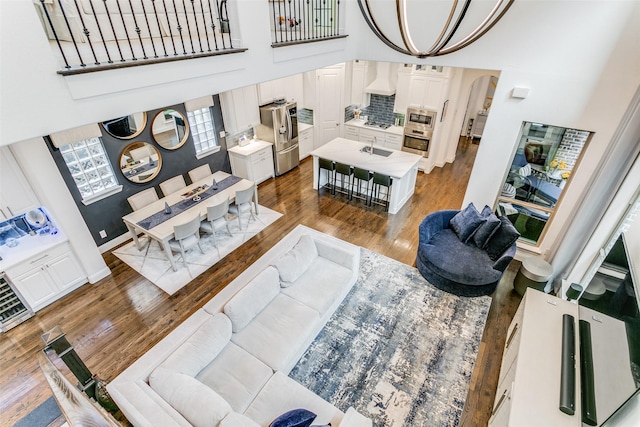 living room with hardwood / wood-style flooring, a towering ceiling, and a chandelier