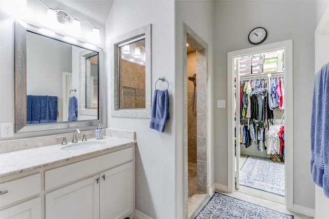 bathroom with a tile shower, vanity, tile patterned floors, and lofted ceiling