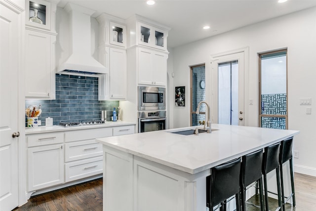 kitchen featuring white cabinetry, sink, a center island with sink, and custom exhaust hood