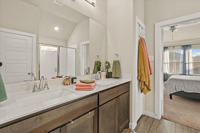 bathroom featuring hardwood / wood-style floors, vanity, a shower with door, and vaulted ceiling