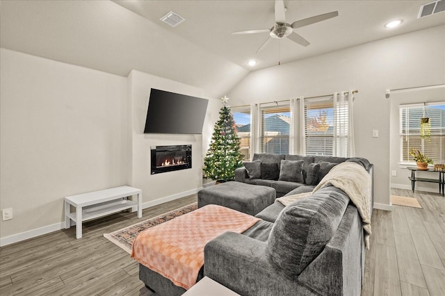 living room featuring ceiling fan, light hardwood / wood-style floors, and vaulted ceiling