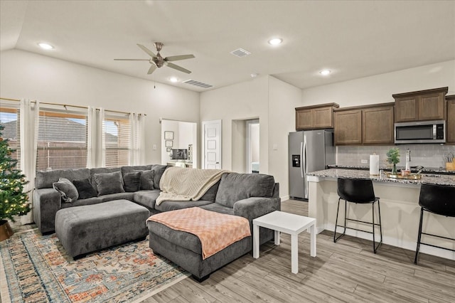 living room with vaulted ceiling, light hardwood / wood-style flooring, and ceiling fan