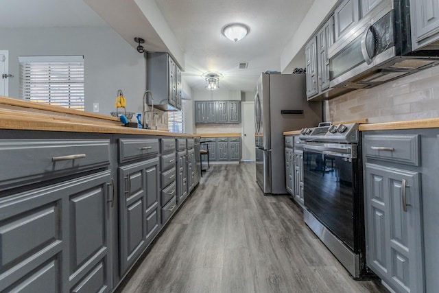 kitchen featuring gray cabinets, appliances with stainless steel finishes, dark hardwood / wood-style floors, sink, and tasteful backsplash